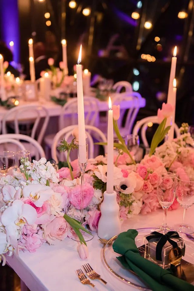 Candlelit dinner table with pink florals, taper candles, and gold-rimmed place settings