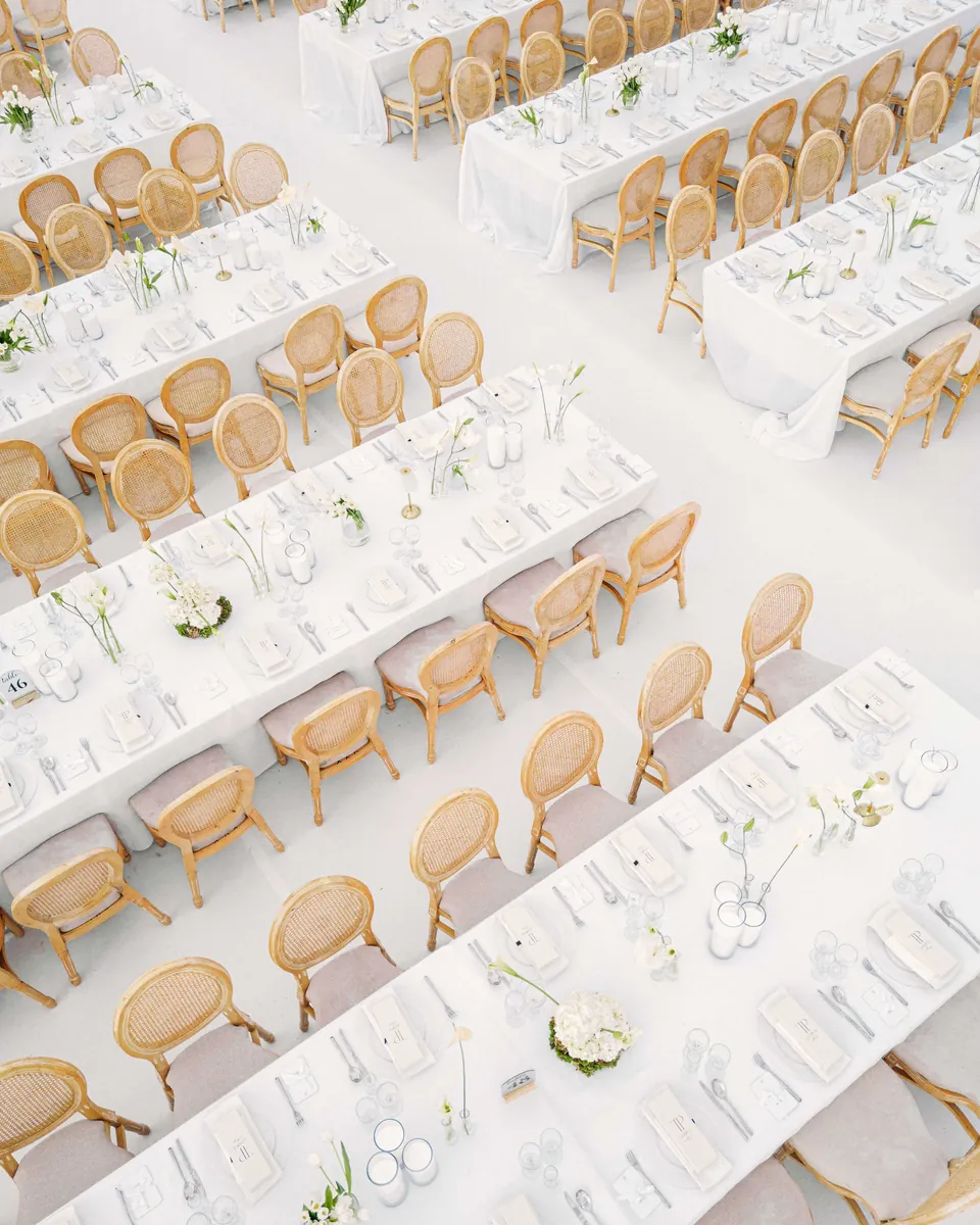 Elevated view of an elegant reception set with long white tables and rows of chairs