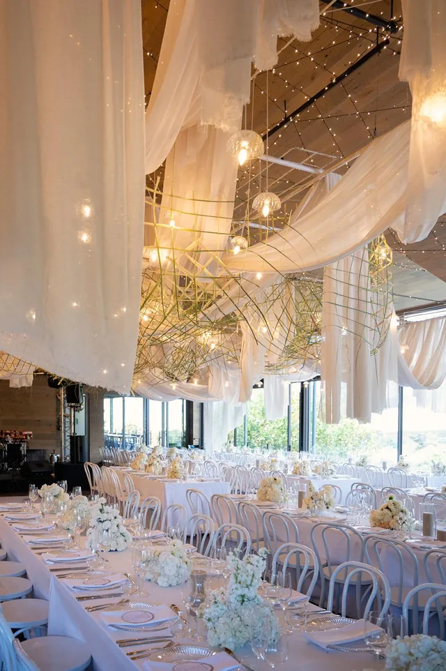 White-draped reception with sculptural lighting and floral tablescapes