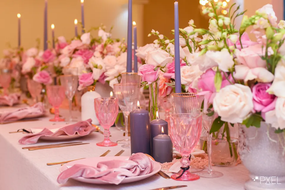 Pink florals, candles and glassware arranged along a dinner table