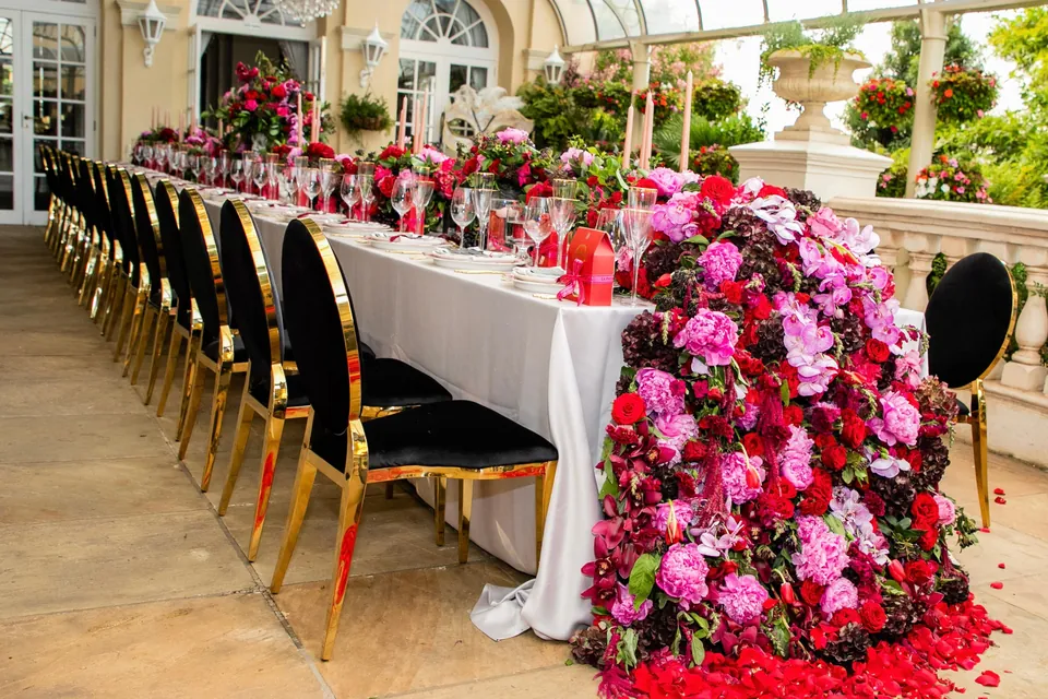 A long floral dining table set beneath a glass conservatory
