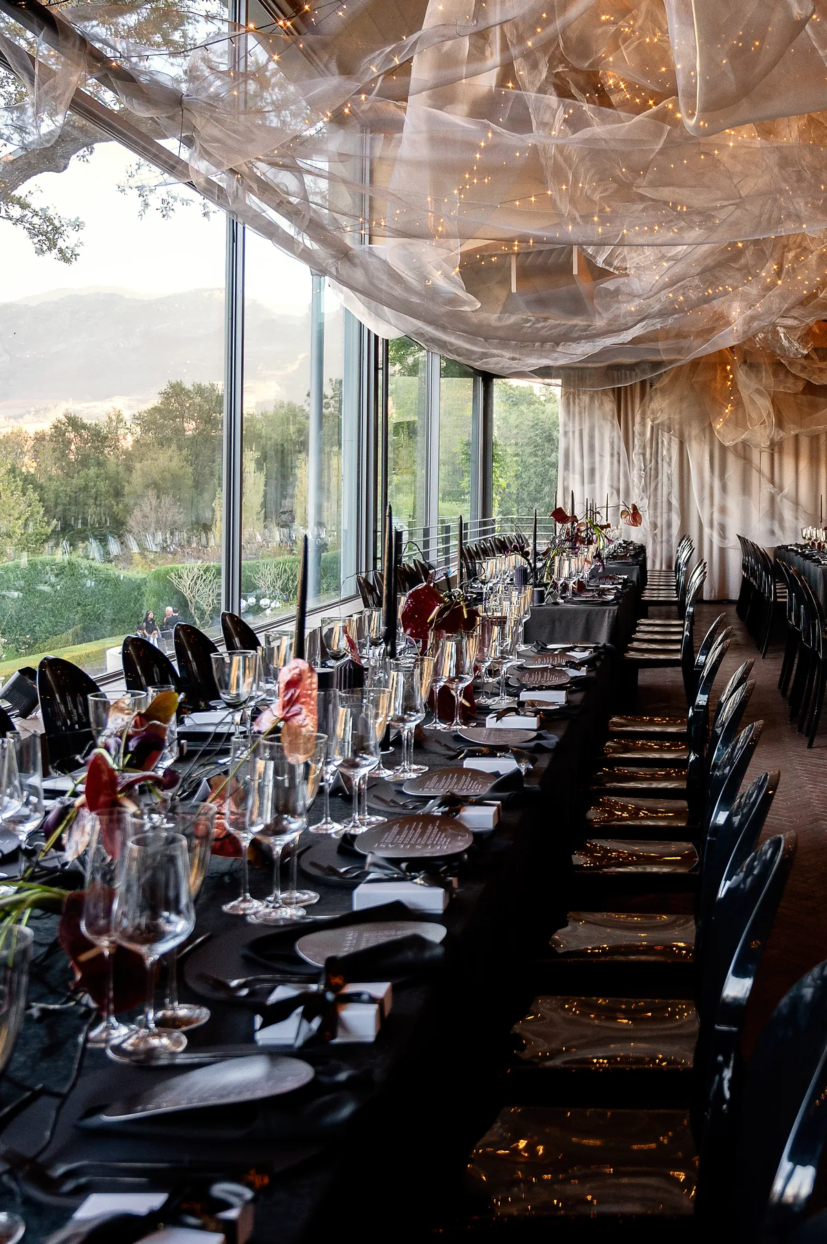 Long black reception table beneath sheer draping