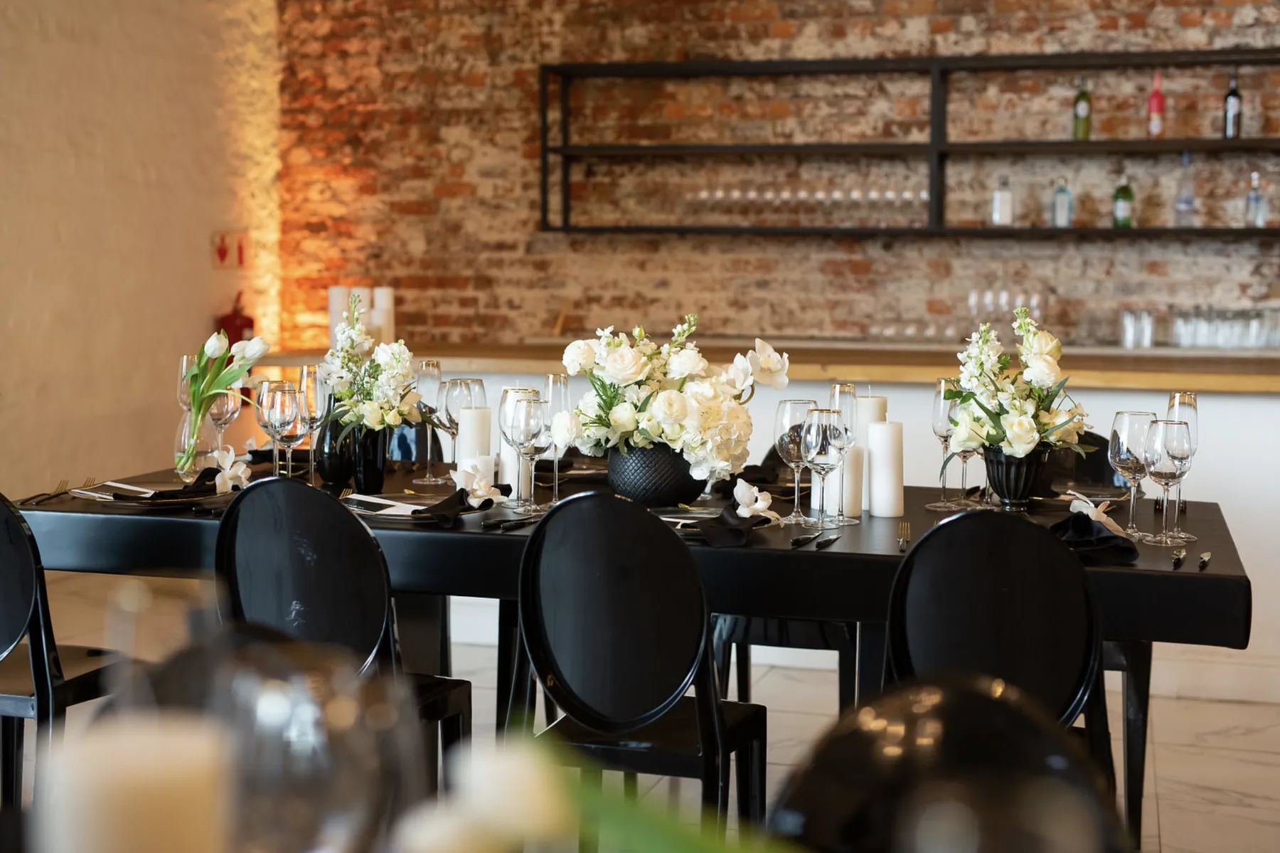 Black dining tables styled with white floral arrangements