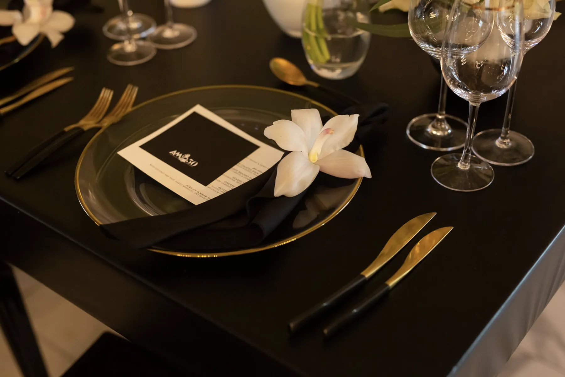 Black place setting with a white flower and personalised menu