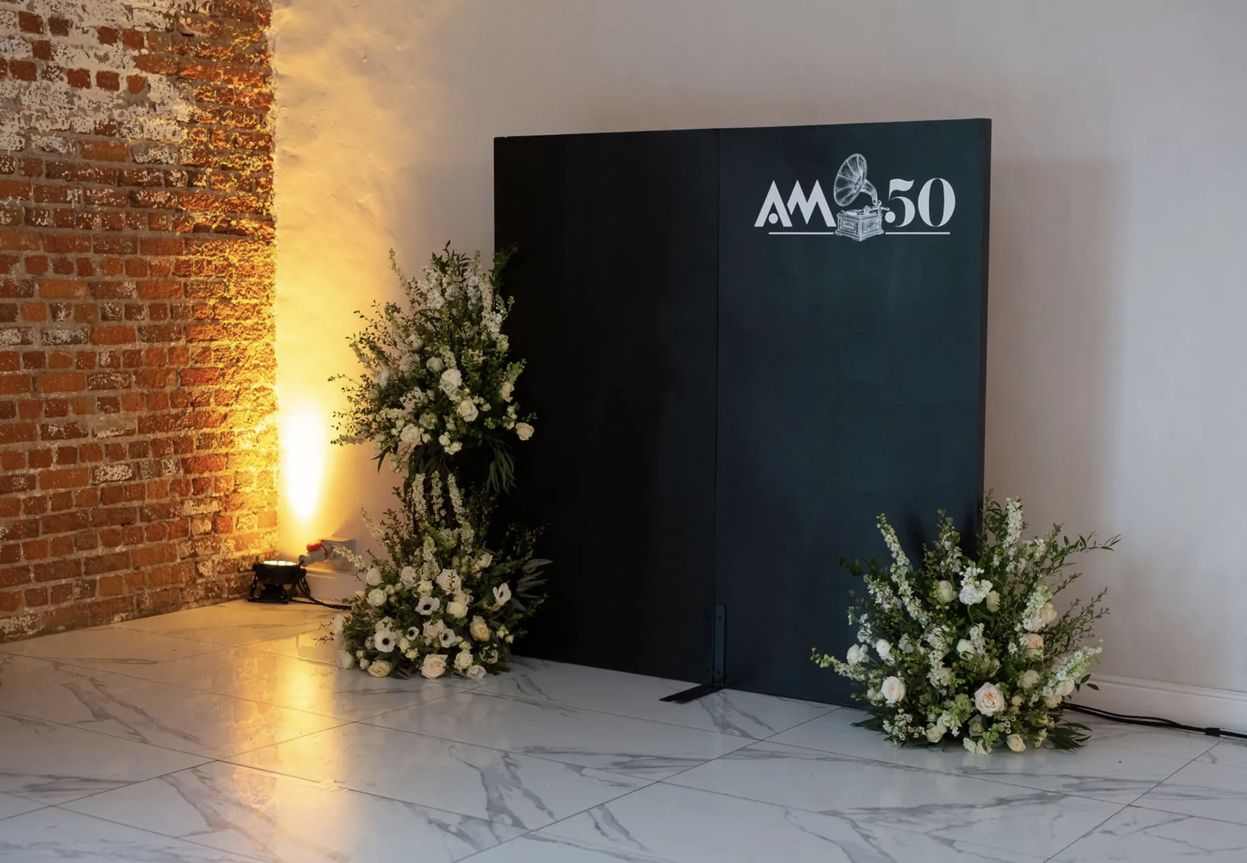 AM at 50 welcome display framed by white flowers