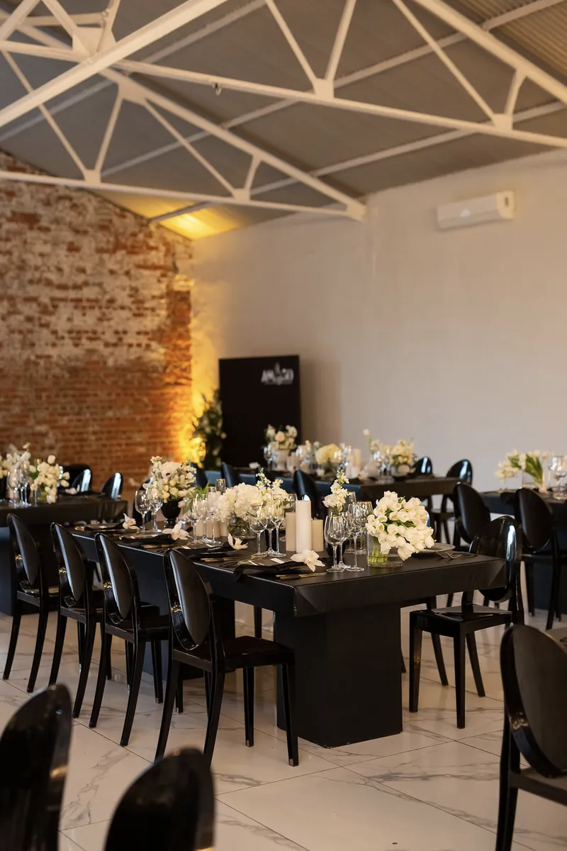 Black dining table styled with white florals and pillar candles
